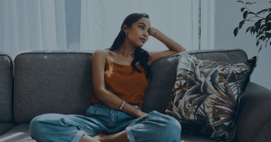 Woman sitting on couch in thought.
